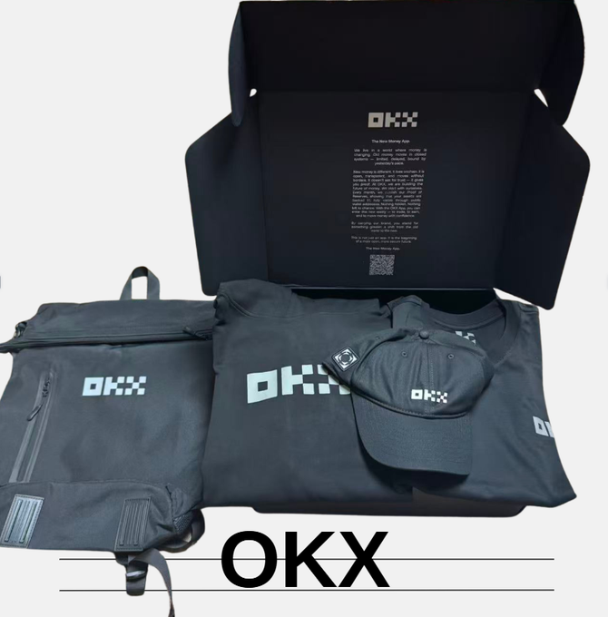 An OKX merchandise box opened to reveal a branded backpack, t-shirt, and cap in dark gray, all featuring the OKX logo, with 'OKX' text overlay at the bottom.