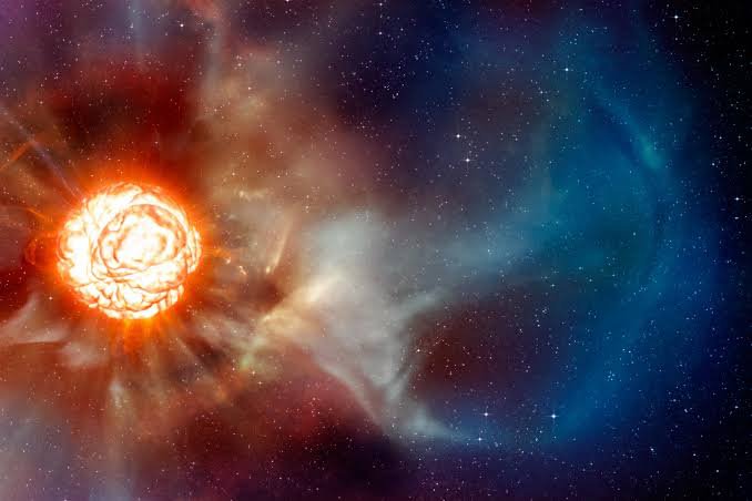 An artistic illustration of a glowing, fiery orange star or sun emitting light and clouds of cosmic gas and dust into a dark, star-filled space with swirling blue and reddish-purple nebula clouds.