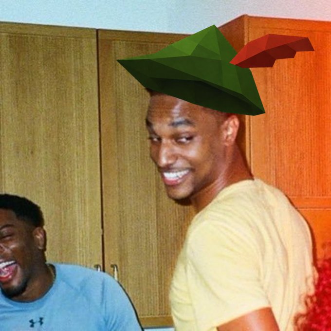 A smiling man in a yellow shirt has been edited to wear a low-poly green Robin Hood-style hat with a red feather, demonstrating the RSTR hat generator in action, while another person in a blue Under Armour shirt laughs in the background.
