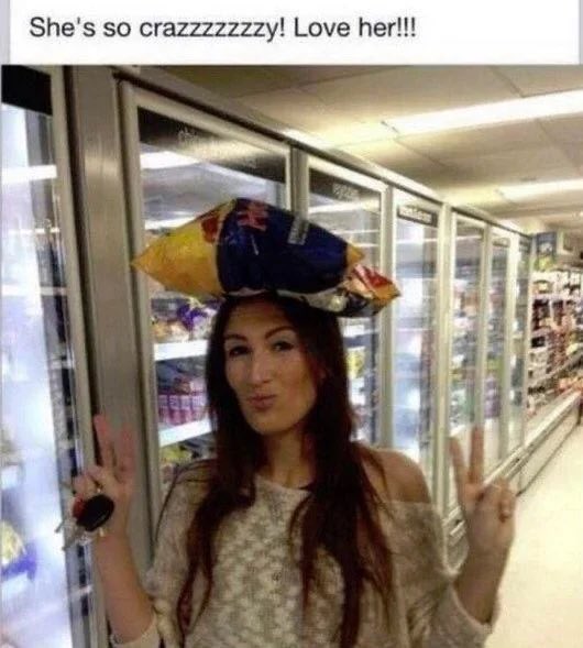 A woman wearing a sweater poses with two peace signs in a store aisle while balancing a bag of chips on her head, with text reading 'She's so crazzzzzzy! Love her!!!'.