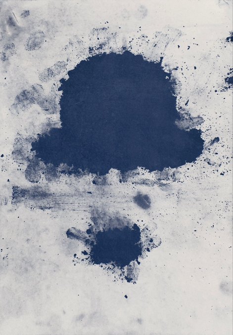 An abstract ink blot art piece with dark blue pigment forming a large cloud-like shape and a smaller shape below it on a white textured paper.