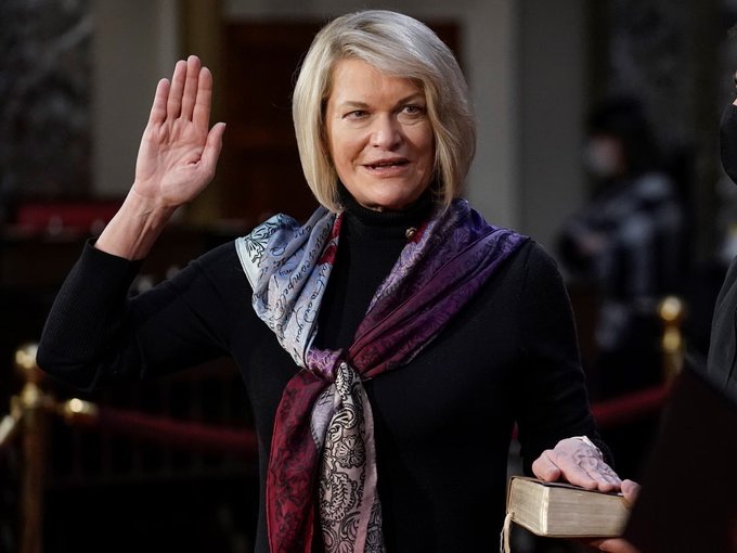 Senator Cynthia Lummis raises her right hand while her left hand rests on a book, taking an oath. The image relates to the post as it likely captures her during the swearing-in ceremony for her role in the U.S. Senate, where she now advocates for the CLARITY Act's funding measures against digital asset fraud.
