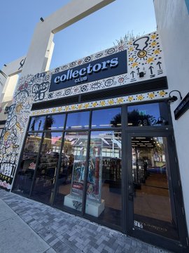 The image shows the storefront of "Collectors" card shop, featuring colorful graffiti-style artwork on the facade and large windows displaying products inside, which aligns with the post highlighting the Wynwood shop as a unique space embracing both physical and digital collectibles.
