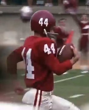 A low-resolution, vintage broadcast clip shows an American football player wearing a crimson jersey with the number 44 catching a pass during a game.