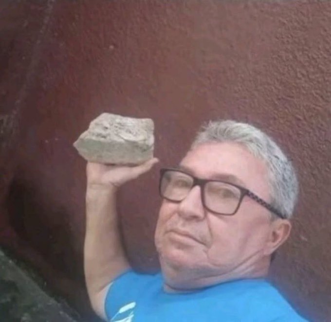 A man with glasses and a blue shirt smiles wryly while holding up a rough stone, as if humorously answering the post by "throwing" the only thing he has at the request for Web3 guidance.