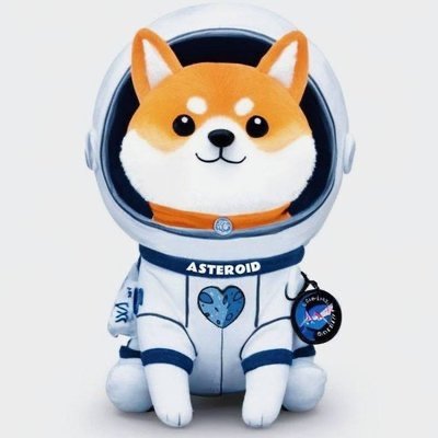 urn-shaped stuffed animal astronaut, dressed in blue and white with a heart on chest, sits against a plain gray background.