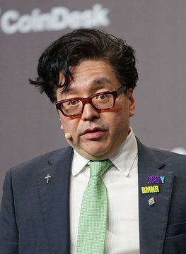 Tom Lee, recognizable by his red-framed glasses and "2025" pin, speaks at a CoinDesk event, providing a visual reference for the reported news that his firm BitMine has acquired an additional 42,197 ETH ($73 million), bringing its total holdings to 5,742,237 ETH at an average buy price of $1,800.
