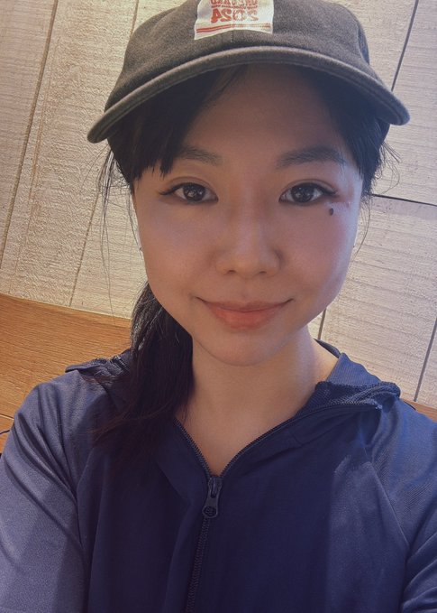 A selfie of a woman wearing a navy 'Brixton Ace' cap and dark blue jacket, posing indoors.
