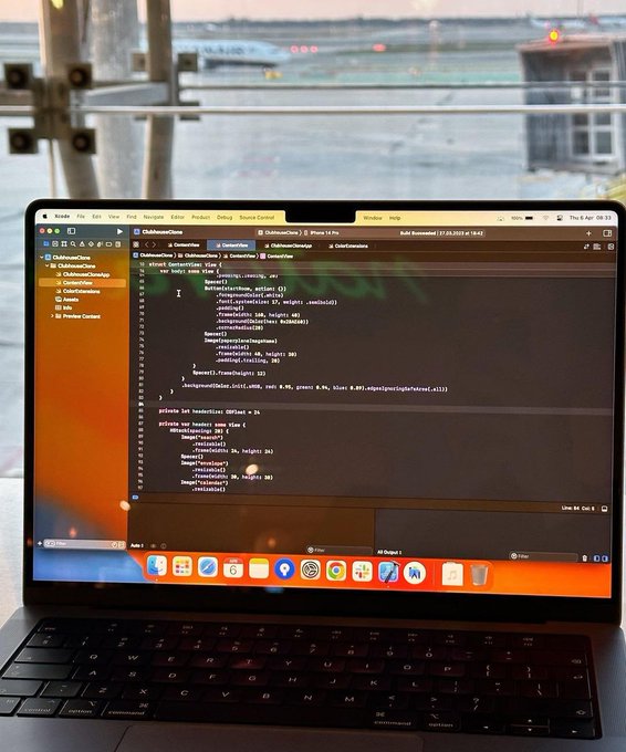 A MacBook displays Swift code in Xcode within a ClubhouseCents project, with the airport runway visible through the window behind it—contrasting the structured programming environment against the blurry travel backdrop.