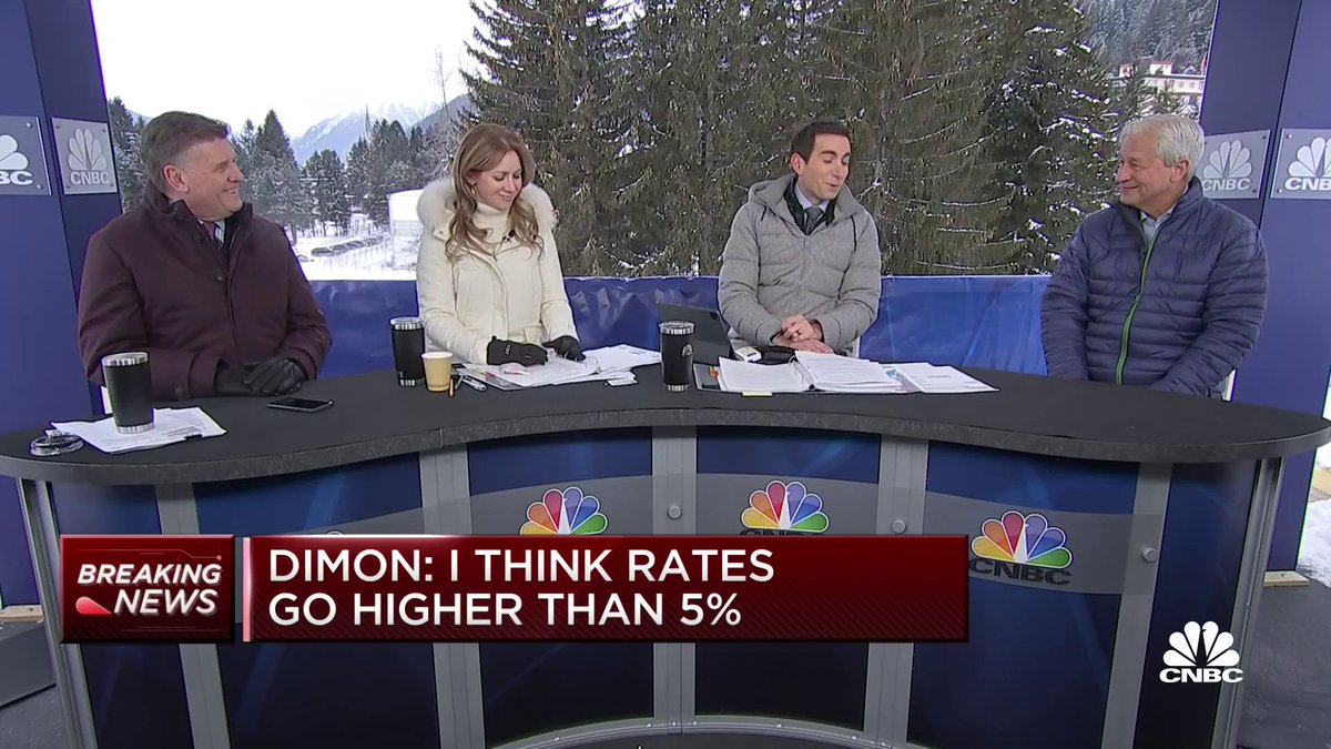 CNBC outdoor broadcast with Jamie Dimon seated at right behind a desk as the lower-third reads “BREAKING NEWS — DIMON: I THINK RATES GO HIGHER THAN 5%.” The image concerns Dimon’s public statements and, with the post, highlights a contrast with his earlier description of Bitcoin as a “hyped-up fraud.”