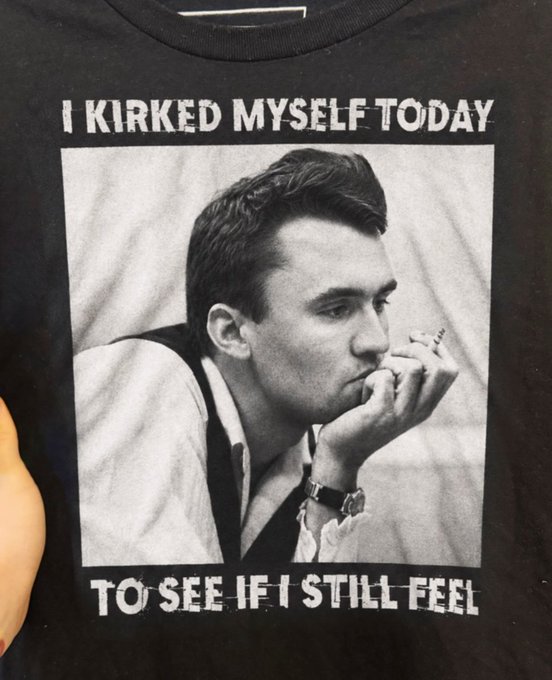 A black t-shirt featuring a black-and-white photo of Johnny Depp smoking a cigarette, with the text 'I KIRKED MYSELF TODAY TO SEE IF I STILL FEEL'.