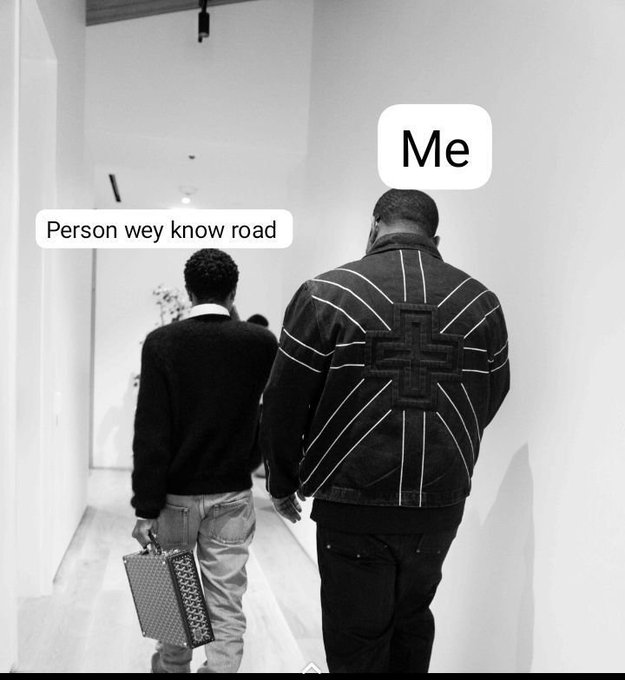 A black-and-white meme photo showing two men walking down a hallway, with one labeled 'Me' wearing a jacket featuring a cross design and the other labeled 'Person wey know road'.