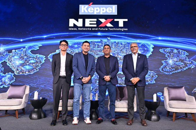 Four men in business attire pose on stage at a Keppel NEXT event, with the backdrop displaying 'Keppel NEXT' and 'Ideas, Networks and Future Technologies' over a glowing world map.