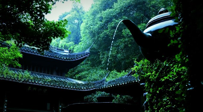A scenic view of traditional East Asian architecture with curved tiled roofs nestled in a lush green forest, with water pouring from the spout of a large dark teapot in the foreground.