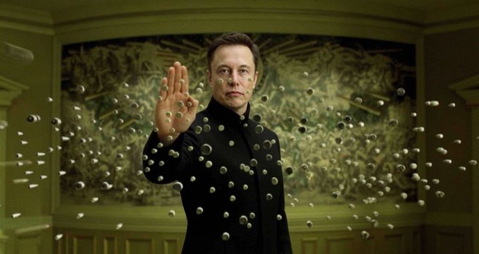 Elon Musk in a black outfit holds up his hand surrounded by floating metallic spheres, with an ornate carved wall in the background.