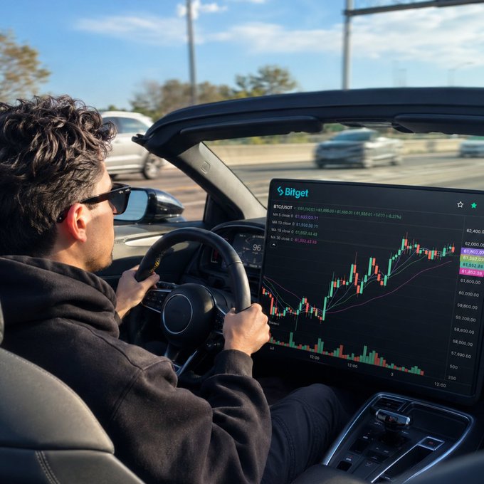 A man in sunglasses drives a convertible while monitoring a BTC/USDT candlestick chart on a Bitget trading tablet, perfectly capturing the "work from anywhere" crypto trader lifestyle. The open-air driving setup paired with live Bitcoin price action reflects the ultimate mobile trading rig.