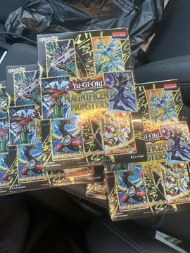 A collection of Yu-Gi-Oh! Monster Strike Booster Packs and boxes are piled on a black surface, with the "GMR" (Game Master) display clearly visible, fitting the post's reference to another GMR session.