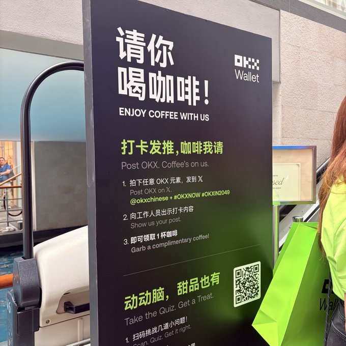 A promotional sign for OKX Wallet reading '请你喝咖啡! ENJOY COFFEE WITH US', detailing instructions to post about OKX Coffee on X for a complimentary coffee.