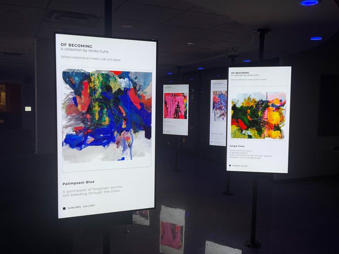 An art gallery exhibition titled 'OF BECOMING: A collection by Ishika Guha' with illuminated digital display panels showing pieces like 'Palimpsest Blue' and 'Jungle Pulse'.