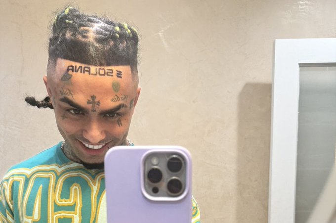 A smiling man with braided hair, facial tattoos including "SOLANA" and "$HYPE" symbols, takes a mirror selfie with a purple iPhone, fitting the post's playful theme about Hypecoin tattoos and Solana price signals.