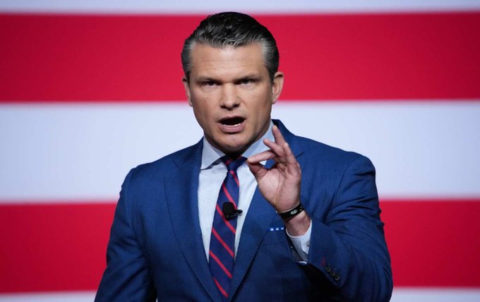 Defense Secretary Pete Hegseth speaks at a podium in front of an American flag backdrop, gesturing with his hand as he addresses an audience, in an image accompanying details about his disclosed financial assets exceeding $3.1 million.