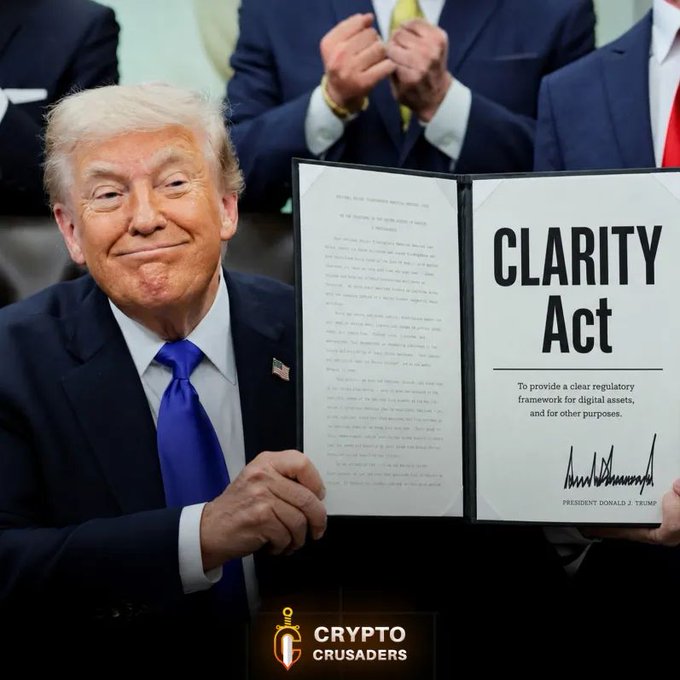 The image features a man dressed in a suit, holding an open book titled "CLARITY ACT" with his hands. The text of the book indicates that it is about promoting clarity and transparency in government actions. The background shows a picture of the White House building, suggesting that this event might be related to a political or governmental context. Additionally, there are two other people visible in the image who appear to be clapping, possibly celebrating an important decision or agreement related to the CLARITY Act.