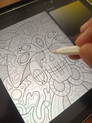 A hand uses an Apple Pencil to draw a detailed, stylized doodle featuring faces and abstract patterns on an iPad screen.