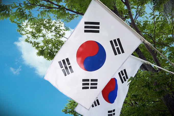 South Korean flags wave against a blue sky, symbolizing the country behind the $367 million stablecoin outflows to overseas exchanges in June, marking 18 straight months of net outflows according to Financial Supervisory Service data.