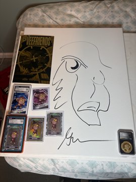 The image shows a hand-drawn sketch of a monkey face signed by Gary Vaynerchuk, displayed on a bed alongside a VeeFriends Series 1 comic book catalog, four character trading cards, and a graded 1/10 Gold Moral Monkey collectible coin, all relating to the VeeFriends IP and supporting the post's thank-you to Gary Vee for donating original artwork to a nonprofit.