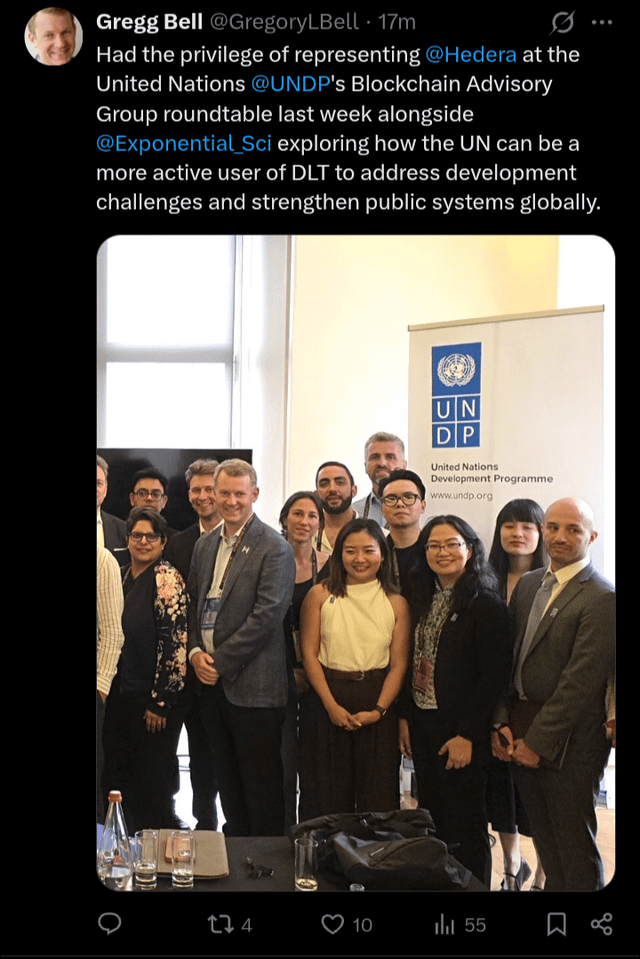 The image shows a group of people posing for a photo, with some standing near a table that has several bottles on it. The caption of the image reads "Focus on what is in the image and how it relates to the post". This suggests that the image might be related to a discussion or event at the United Nations involving blockchain technology and its potential applications in various fields such as finance, healthcare, and more.