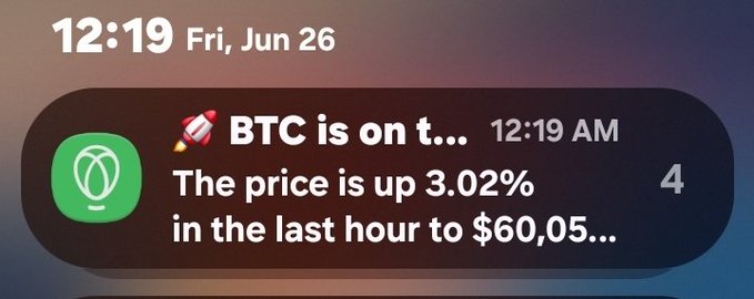 An iPhone lock screen notification at 12:19 AM on Fri, Jun 26 shows a BTC alert stating the price is up 3.02% in the last hour to $60,05..., tying into the post's focus on Bitcoin and other cryptocurrencies like $HBAR, $XRP, and $XLM.