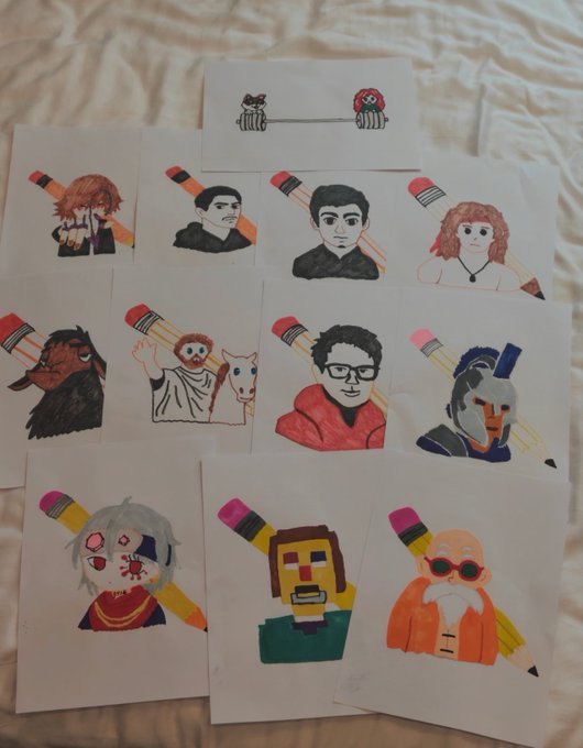 A collection of hand-drawn character portraits on white paper laid out on a bed, each featuring a person's face drawn on top of a pencil illustration.