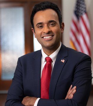 A smiling Vivek Ramaswamy in a navy suit and red tie poses in front of an American flag. The image relates to news of his asset management firm Strive purchasing 18 Bitcoin, expanding its significant BTC holdings.