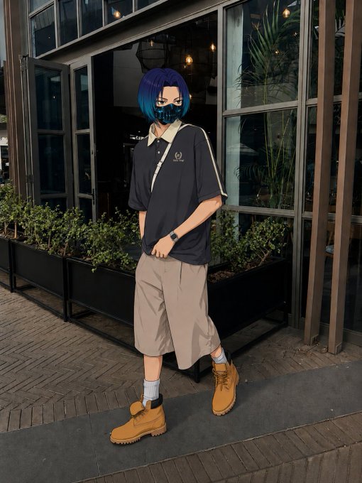 A cosplayer with blue hair wearing a skull-patterned face mask, black polo shirt, beige shorts, and tan boots, posing outside a building with large windows and greenery.