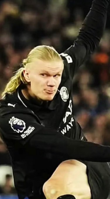 The image shows a blonde soccer player in a black Premier League jersey with "No Room for Racism" and "PUMA" logos visible, captured mid-celebration with one arm raised. The post's "How it started vs how it's going" theme suggests this is the "going" phase, depicting a confident, successful moment in his career, likely referencing his evolution into a prominent footballer.