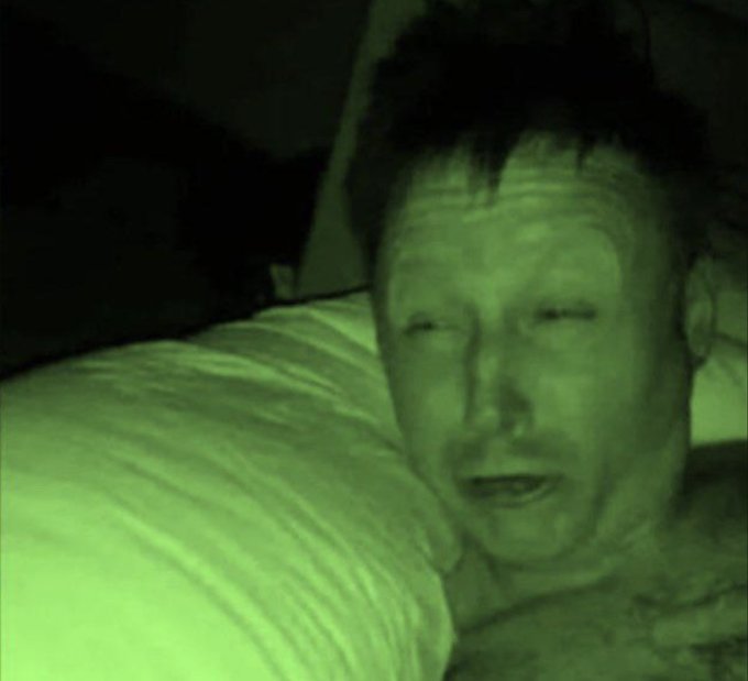 A grainy night-vision style image shows a close-up of a man's face illuminated by a green glow as he lies next to a white pillow, appearing to speak. The eerie, sleep-talking aesthetic pairs with the "Good morning" message to humorously suggest a crypto enthusiast waking up still thinking about their Bitcoin holdings after a long night of stacking.
