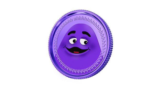 A purple coin-like token featuring a smiling grape emoji face on a white background.
