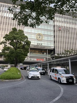Exterior view of JR (Japan Railways) Shinjuku Station with taxis arriving at the entrance.