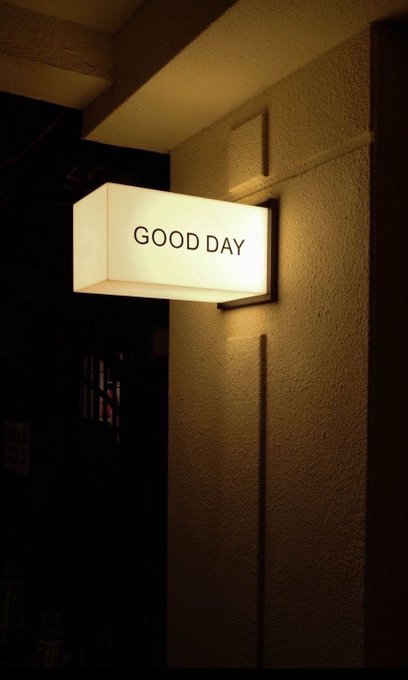 A glowing rectangular wall light in a dark setting, displaying the text 'GOOD DAY'.