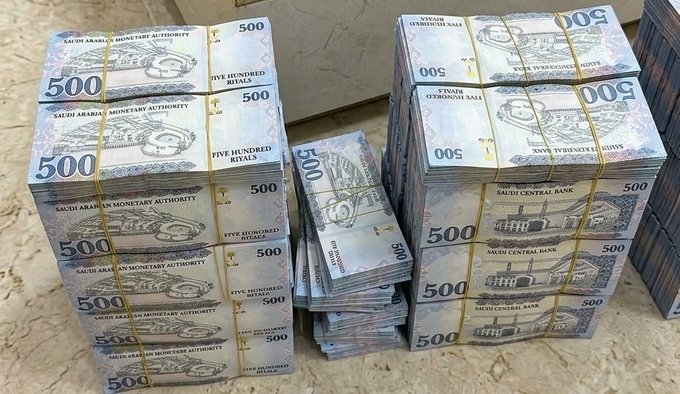 Large stacks of 500 Saudi Arabian Riyal banknotes bundled together with yellow bands.