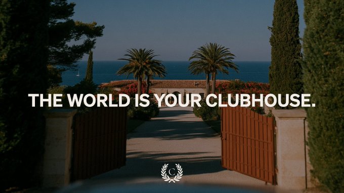 An open gate framed by cypress trees and palm trees leads toward a coastal estate overlooking the sea, with the bold white text "THE WORLD IS YOUR CLUBHOUSE." overlaid across the scene and a small laurel wreath emblem centered at the bottom. The image visually reinforces the post's message of exclusive, borderless luxury by depicting the serene entryway of a Mediterranean private retreat—symbolizing the kind of privileged access Corn's global membership unlocks for its members.