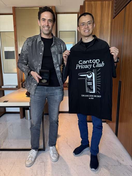 Two men smile while holding up a black "Canton Privacy Club" t-shirt featuring a padlock graphic and the text "Privacy is a Human Right. Educate. Join [NYC][Zur][HK][BULD] est. 2023," along with a small black box displaying the "$CC" cryptocurrency token, suggesting the shirt is a promotional gift for the upcoming $CC listing teased in the caption to @cz_binance.