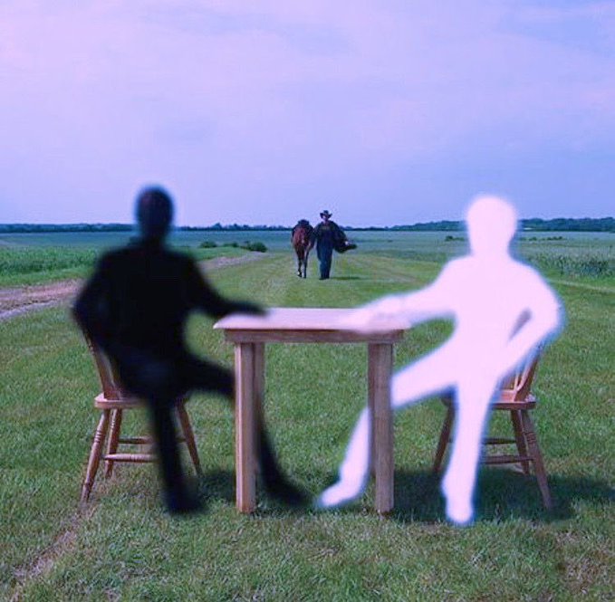 A surreal image showing a dark silhouette and a glowing white silhouette seated at a wooden table in a grassy field, while a cowboy leads a horse in the background.