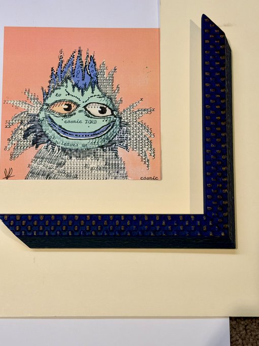 A mixed-media artwork showing a quirky, scribbled blue and green creature labeled 'COSMIC Toid' on a peach background, paired with a dark blue patterned picture frame corner.