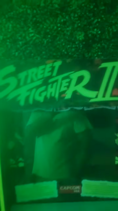A green-tinted photo of a Street Fighter II arcade cabinet by Capcom, showing the marquee and screen.