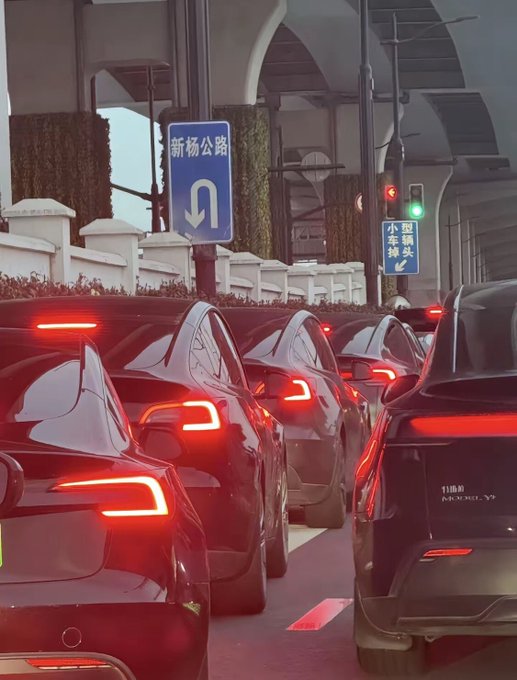 The image shows a busy street filled with cars driving down the road, including some that are turning left or right as they navigate through traffic. The scene captures the essence of urban life and transportation, highlighting the hustle and bustle of city living.