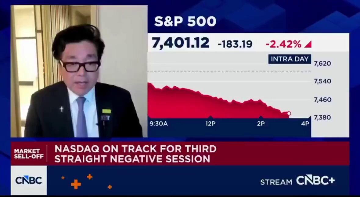 The image shows a man wearing glasses, standing behind a computer screen with a news program displayed on it. The news program has a headline that reads "Nasdaq on Track for Third Straight Negative Session", indicating a decline in the stock market. The man is talking about this negative trend and its impact on the economy.
