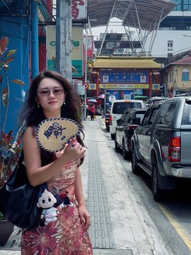 A young woman stands on a bustling city street holding a decorative fan, with a small plush charm attached to her bag. The image appears to showcase travel accessories like the passport holder, complementing the post's promotion of travel-friendly items with #HTX branding.

(Note: No specific text, numbers, or tickers beyond "#HTX" are clearly visible in the image itself.)