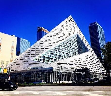 A striking modern pyramid-shaped building dominates a city street under a clear blue sky, likely the VIA 57 West residential tower in New York City. The image appears to serve as a backdrop for a testimonial about the AVAX Summit, an institutional crypto/blockchain networking event held in NYC that brought together notable industry figures.