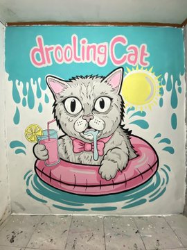 A mural-style illustration shows the "Drooling Cat" mascot—a drooling cartoon cat with a pink bow tie floating in a pink inner tube and holding a cocktail—set against a turquoise background with dripping paint accents and a sun. The image visually promotes the "Drooling Cat" meme competition, tying its playful branding to the contest's call for users to integrate the character IRL for a chance to win cash prizes.